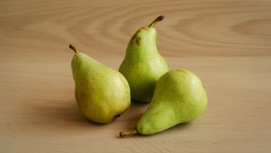 An image of three green pears on a drawing table.